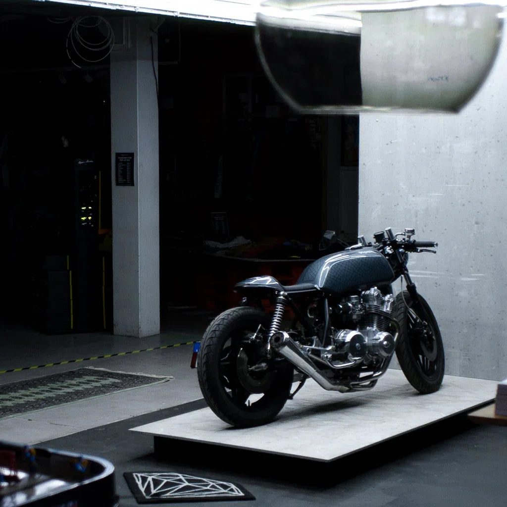 Custom vintage motorcycle on display in a modern garage setting, showcasing polished metal parts