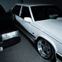 White Volvo sedan with clean, polished finish and custom wheels parked in garage