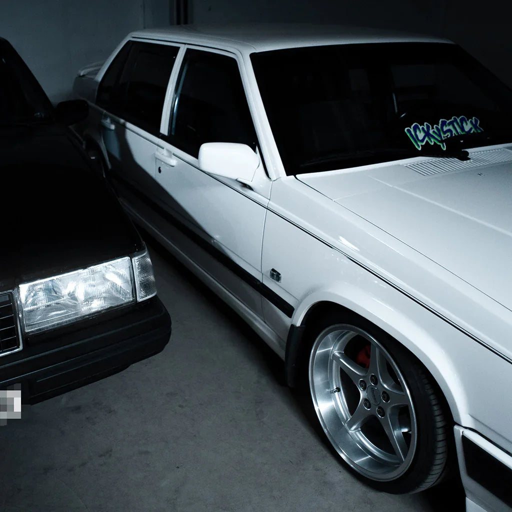 White Volvo sedan with clean, polished finish and custom wheels parked in garage